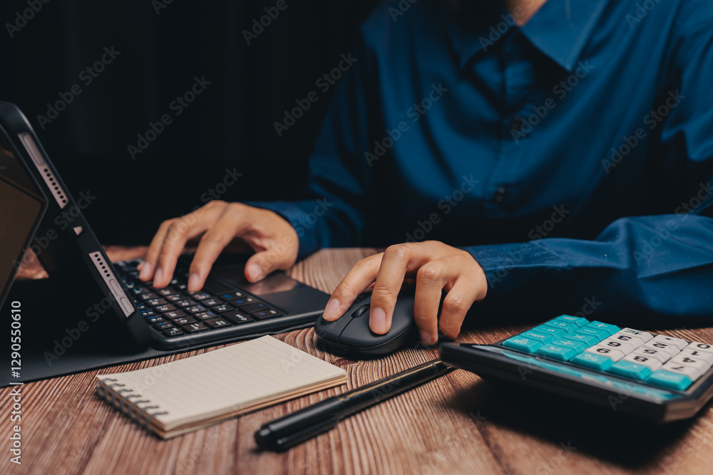 Poster person using laptop and mouse with notepad and calculator on table, business concept