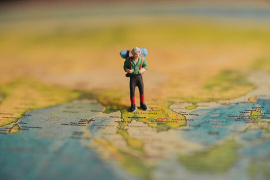 Miniature Traveler on World Map with Backpack and Adventure Spirit, Travel concept