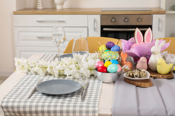 Festive table setting with flowers, Easter bunny and painted eggs