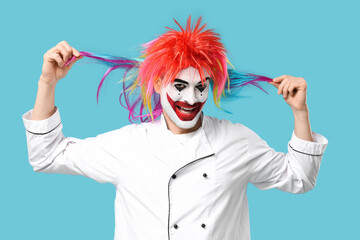 Smiling young man as clown cook on blue background