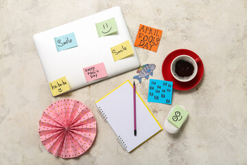 Laptop, notebook, cup of coffee and sticky notes on grunge background. April Fools Day prank