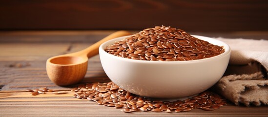 Brown flax seeds in a white bowl positioned center-left on a rustic wooden background with a wooden scoop nearby for a natural look.