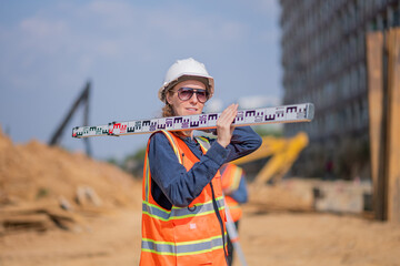 Construction surveyor or engineer working construction site leveling rod measuring angles and...