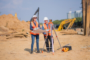 Construction surveyor or engineer working construction site blueprint and theodolite mounted tripod...