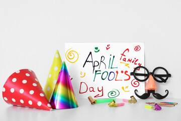 Poster with text APRIL FOOL'S DAY, funny disguise, party hats and whistles on white background
