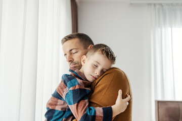 Fototapeta na wymiar Portrait of gentle father hugging his beloved little son at home.