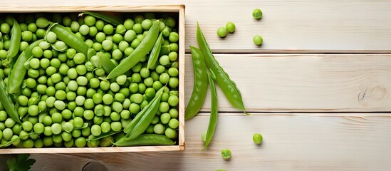 Fresh green peas in a wooden box on a rustic white table with scattered peas and pea pods highlighted against a clean background.