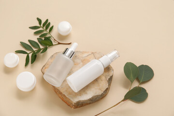 Composition with jars, bottles of cosmetic products, stone and twigs on beige background