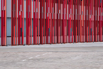 Vibrant red architectural installation with vertical metal elements in an open plaza.