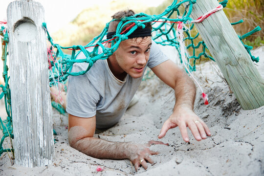 Fitness, man and crawl with obstacle outdoor for strength training, endurance and mobility growth. Person, course exercise and challenge with sports workout, survival assessment and bootcamp activity