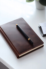 Elegant leather-bound notebook with a sleek black pen on a desk