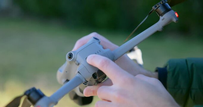 Close-up of hand turning on a DJI Air 3S drone, showing battery status indicator lights in an outdoor environment. Ideal for tech, drone, and tutorial content