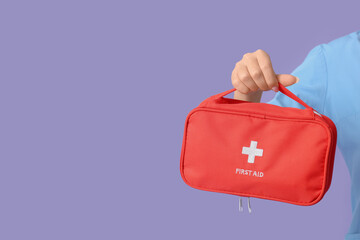 Female hand with first aid kit on lilac background