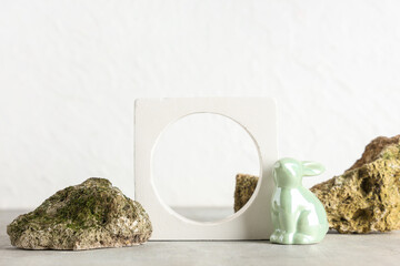 Decorative podium with toy bunny and stones on white background. Easter celebration