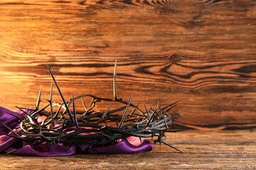 Crown of thorns with purple cloth on wooden background, closeup. Good Friday concept