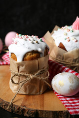 Board with sweet Easter cakes and eggs on black wooden table