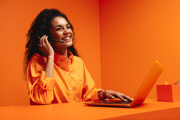 Smiling woman customer support agent in vibrant orange monochromatic office setting