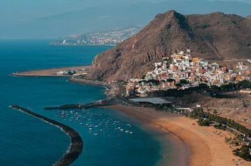 Aerial view of a coastal town with a sandy beach and blue waters in Tenerife