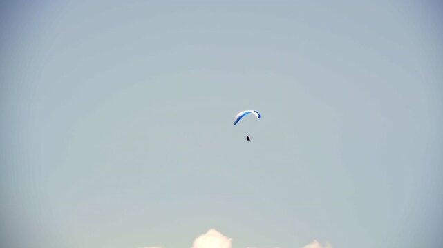 Paraglider performing acrobatic tricks, spirals, and twists high in the sky. Extreme paragliding maneuvers captured in mid-air, showcasing skill, adrenaline, and precision flying