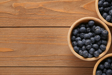 Bowls with sweet fresh blueberries on wooden background