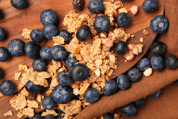 Wooden board with sweet fresh blueberries and corn flakes on napkin, closeup