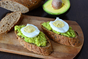 Avocado Toast with Egg on cutting board on wooden kitchen table