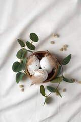 Delicate easter composition with decorative eggs in the wooden bowl with branches of eucalyptus. 