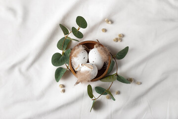 Delicate easter composition with decorative eggs in the wooden bowl with branches of eucalyptus and catkins.