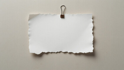 Naklejka premium Torn Paper Memo with Wavy Edges, Held by Rusted Paperclip on Neutral Backdrop