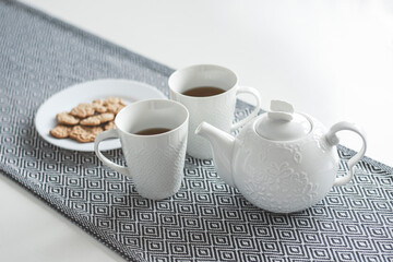 White ceramic teapot, tea and cookies on the table