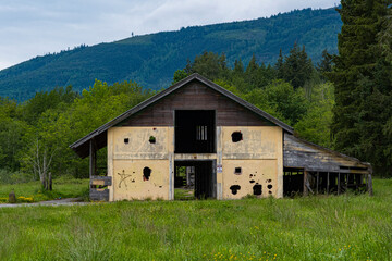 An abandoned building with signs of decay sits amid lush greenery and rolling hills, evoking feelings of nostalgia, history, and the passage of time in nature.