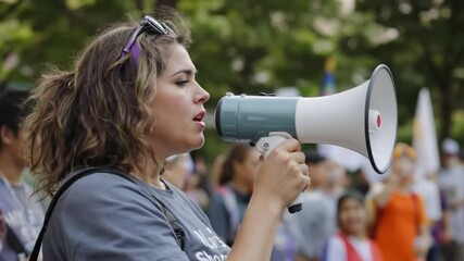 Mid adult woman leading a demonstration using a megaphone outdoors