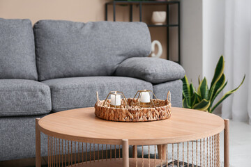 Wicker tray with beautiful candles on table at home, closeup