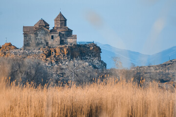 Monastery on the lake shore. Churches on the river bank. Winter landscape with church and lake. Monastery in nature. Frozen lake and rocky mountains