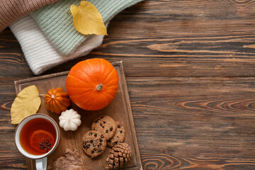 Composition with cup of tea, cookies, sweaters and autumn decor on wooden background