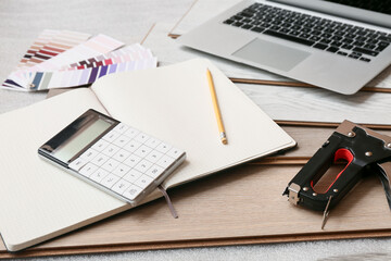 Tools, calculator, laptop and laminate boards on floor