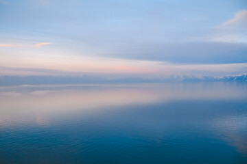 Fototapeta premium Beautiful sunset over the lake. Sunrise on the sea. Beautiful landscape with lake, mountains and sunset. Reflection in the water