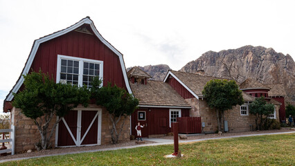 Obraz premium A picturesque red barn set against a stunning backdrop of majestic mountains, showcasing rustic charm and the serenity of rural life in a beautiful landscape.