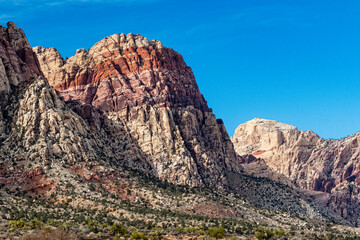 Obraz premium Striking image of colorful rock formations illuminated by bright sunlight, showcasing the beauty and diversity of nature in a clear blue sky backdrop.