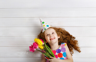 Happy girl smiling looking up, holding bouquet of tulips.