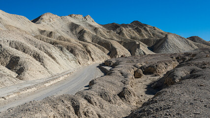 A breathtaking view of a dry desert landscape with rugged mountains and a clear blue sky, showcasing the unique textures and colors of the natural terrain.