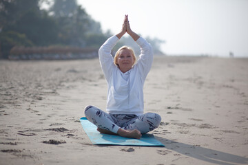 Middle-aged woman does yoga on the shore of the Indian Ocean early in the morning