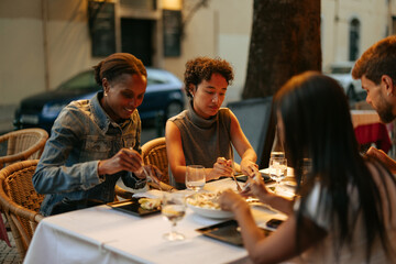 Friends enjoying dinner together at outdoor restaurant