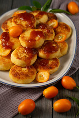 Delicious cheesecakes with delicious kumquats and citrus jam in a large oval plate, close-up