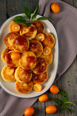 Delicious cheesecakes with delicious kumquats and citrus jam in a large plate, top view