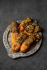 Chocolate and pistachio eclair cookies on a vintage metal plate, top view
