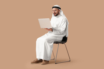 Arab businessman working with laptop in chair on beige background