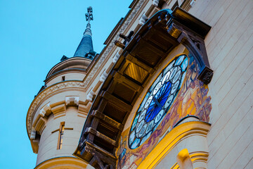 A close-up of the iconic clock tower of the Palace of Culture in Iași, Romania, framed by blooming tulips in the foreground