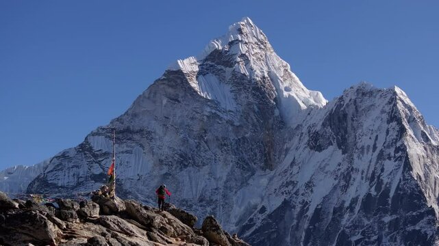 Majestic Mount Everest towers over a mountaineer standing on Nangkartshang Peak, showcasing the challenging yet rewarding pursuit of conquering Himalayas