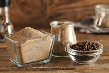 Jar and glass bowl of black pepper powder with peppercorns on wooden background